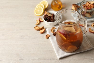 Delicious compote with dried fruits in glass jug on light wooden table, space for text