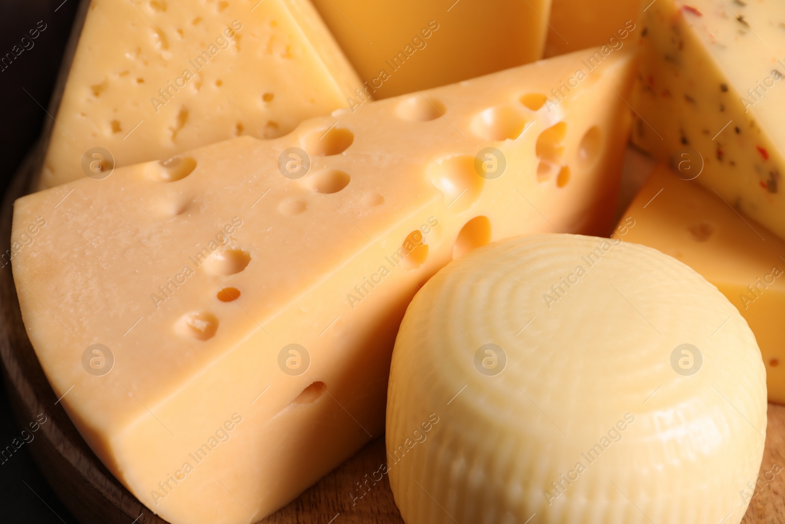 Photo of Different kinds of tasty cheese on wooden plate, closeup