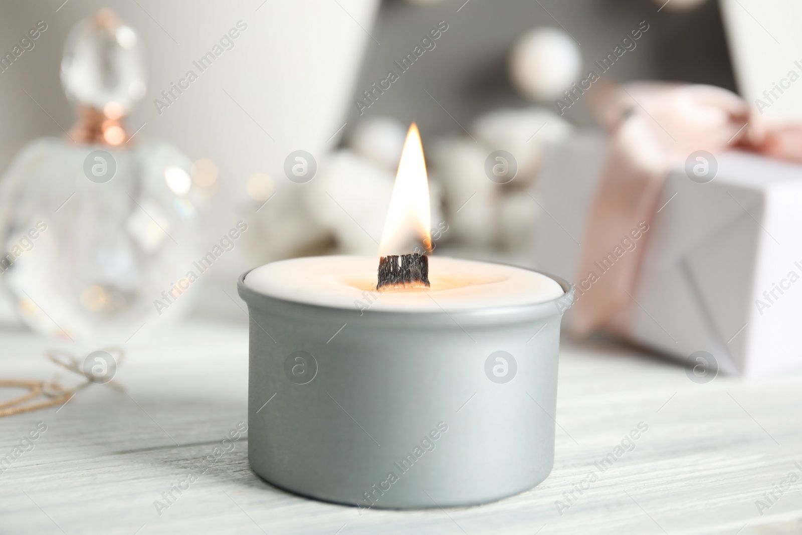 Photo of Beautiful burning candle on white wooden table, closeup