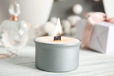 Beautiful burning candle on white wooden table, closeup