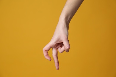 Woman imitating walk with hand on yellow background, closeup. Finger gesture