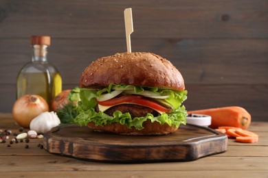 Delicious vegetarian burger and ingredients on wooden table