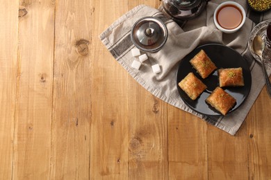 Photo of Delicious sweet baklava with pistachios served on wooden table, flat lay. Space for text