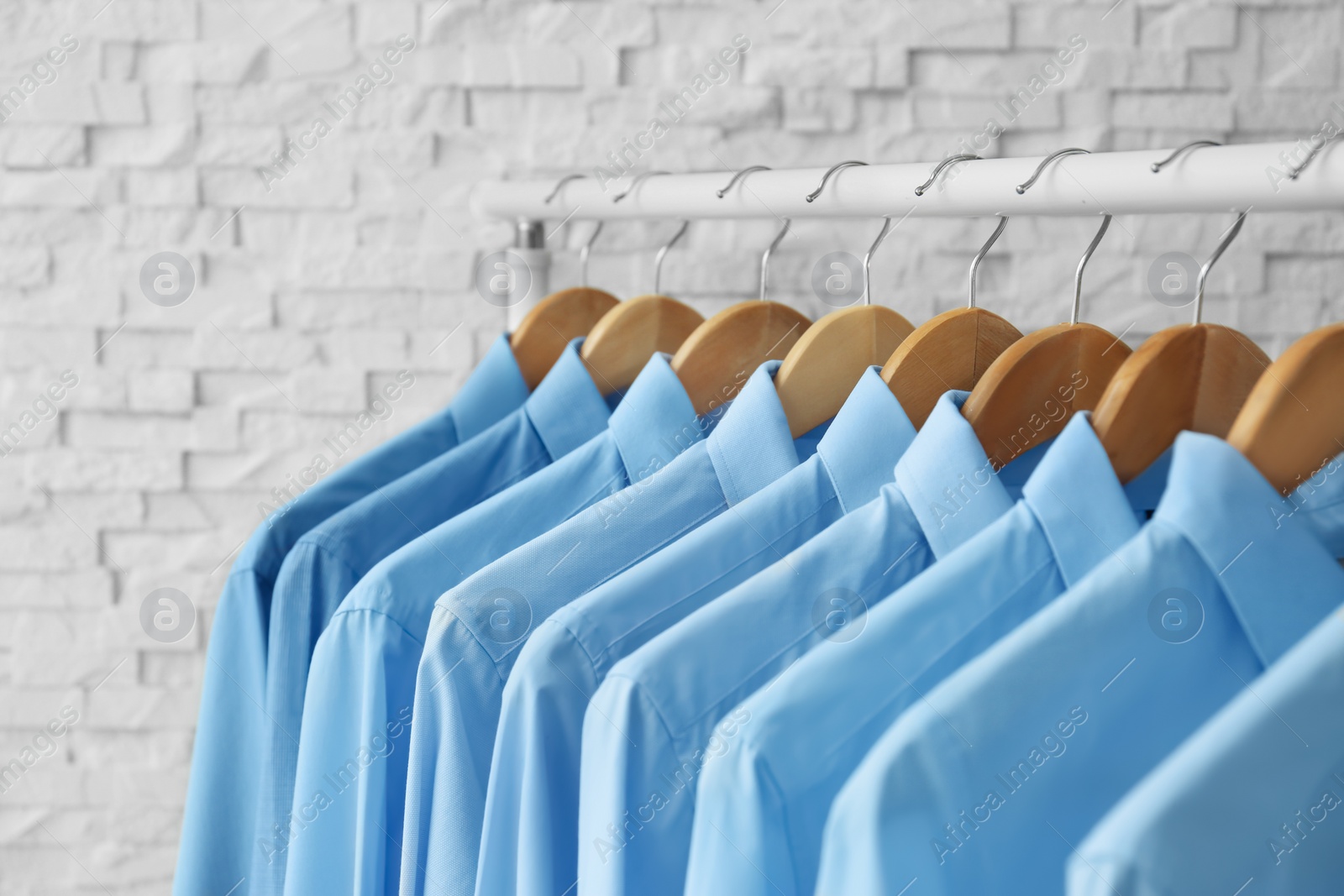 Photo of Rack with clean clothes on hangers after dry-cleaning indoors