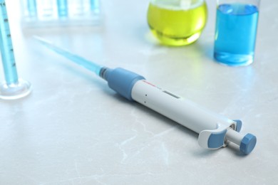 Laboratory analysis. Micropipette with liquid on light grey marble table, closeup