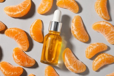 Photo of Aromatic tangerine essential oil in bottle and citrus fruit on grey table, flat lay