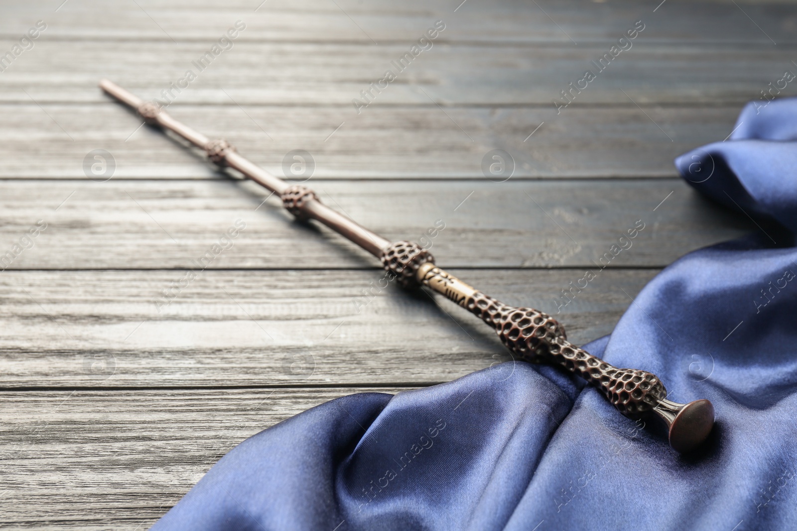 Photo of Old magic wand and fabric on grey wooden table, closeup