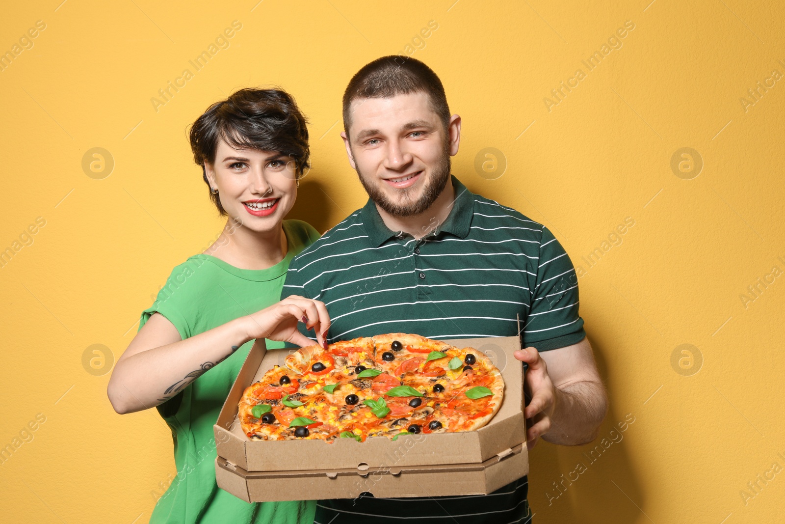 Photo of Attractive young couple with delicious pizza on color background