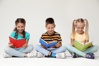 Photo of Little children reading books on grey background