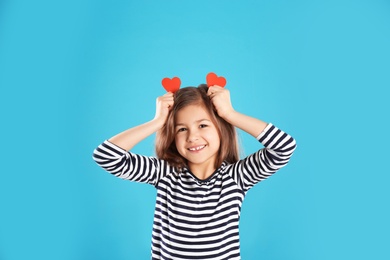 Portrait of girl with paper hearts on color background