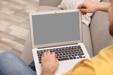 Photo of Young man using video chat on laptop in living room, closeup. Space for design