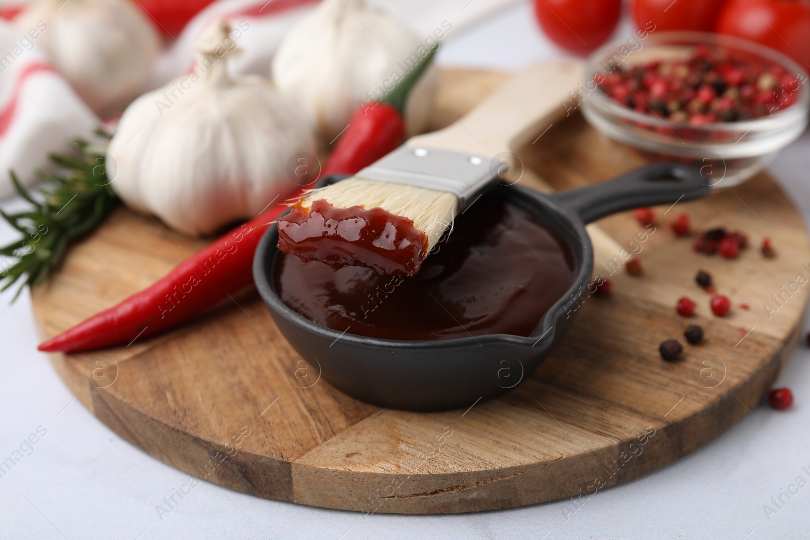 Photo of Marinade in gravy boat and basting brush on white table, closeup