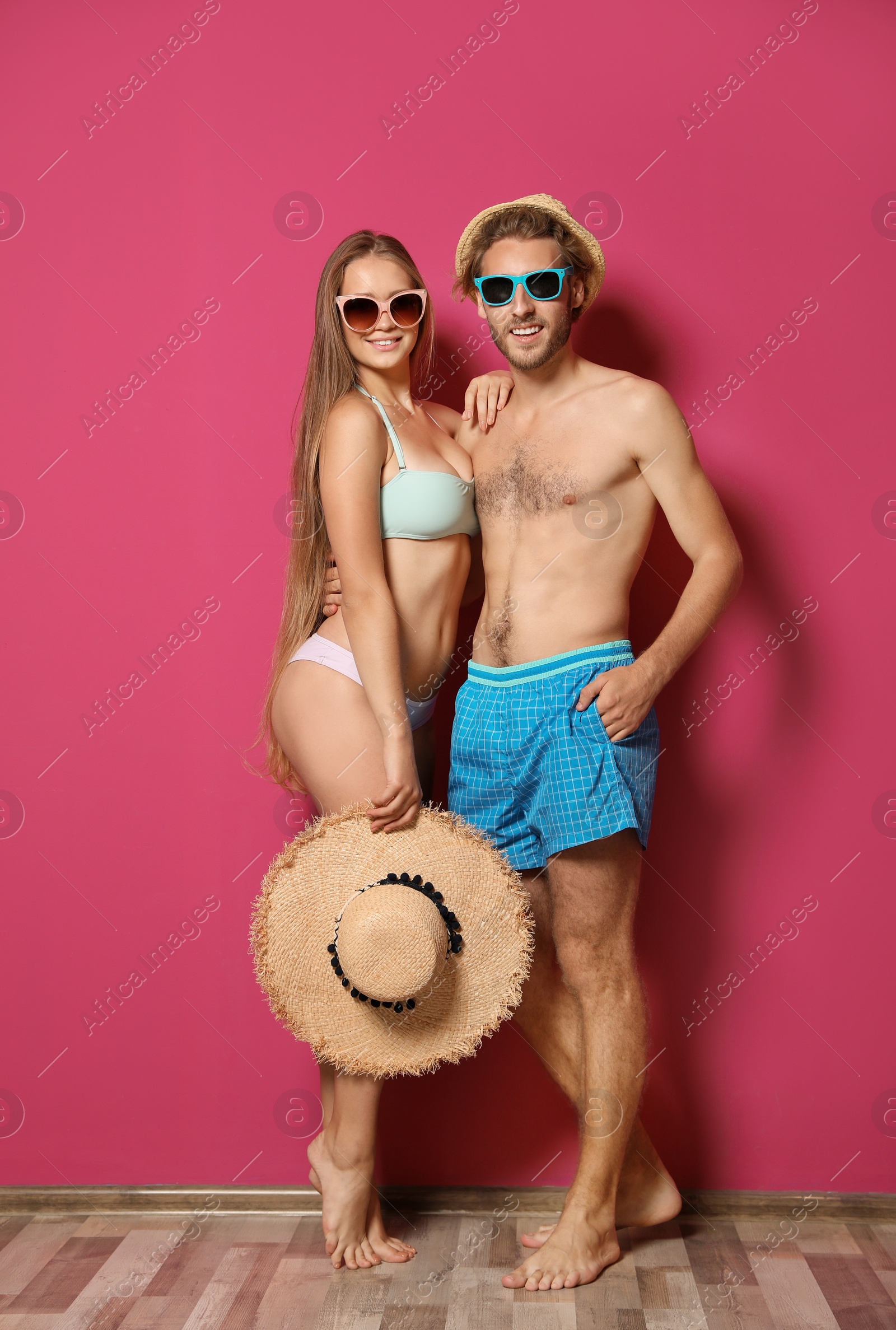 Photo of Happy young couple in beachwear against color wall