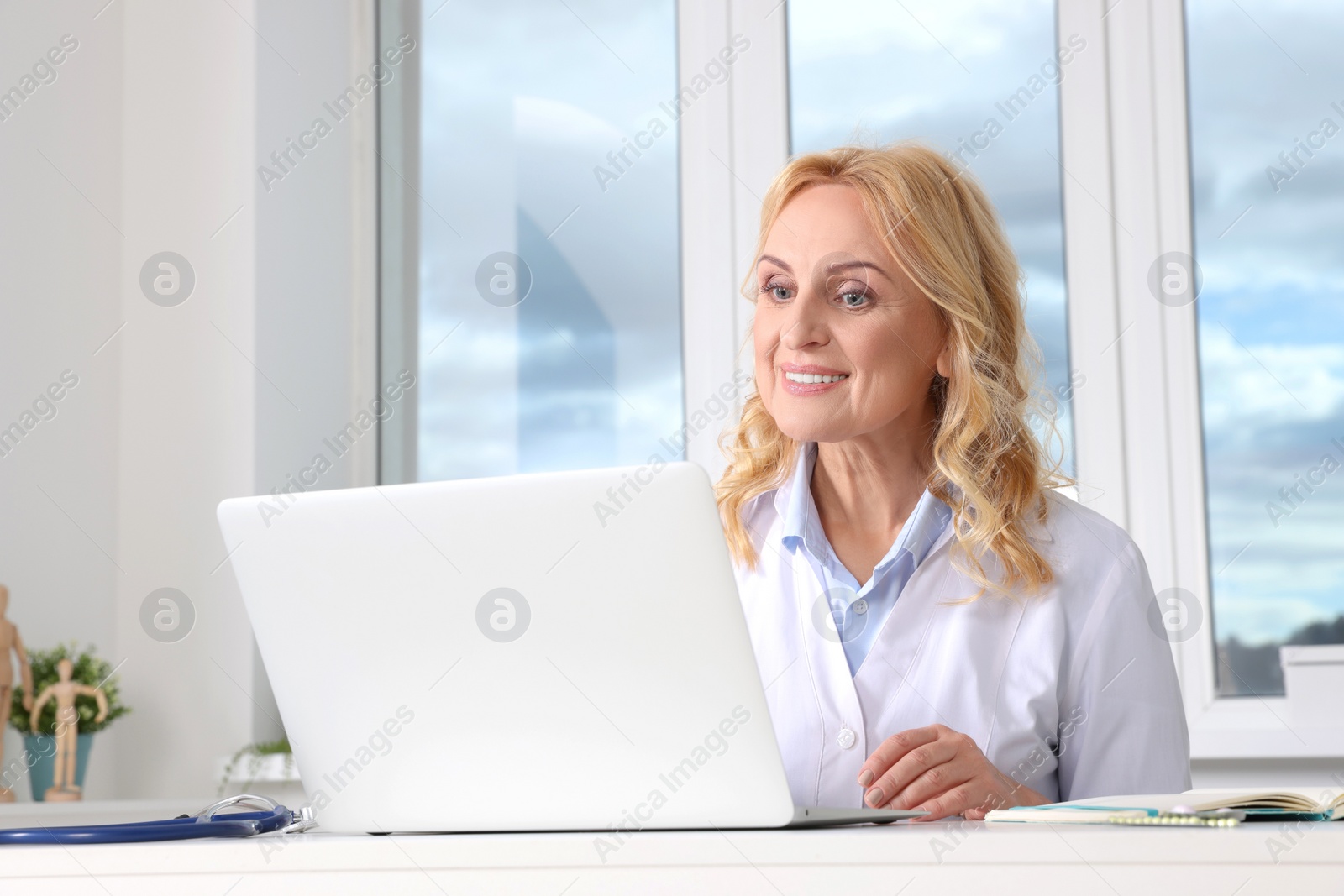 Photo of Doctor with laptop consulting patient in clinic. Online medicine concept