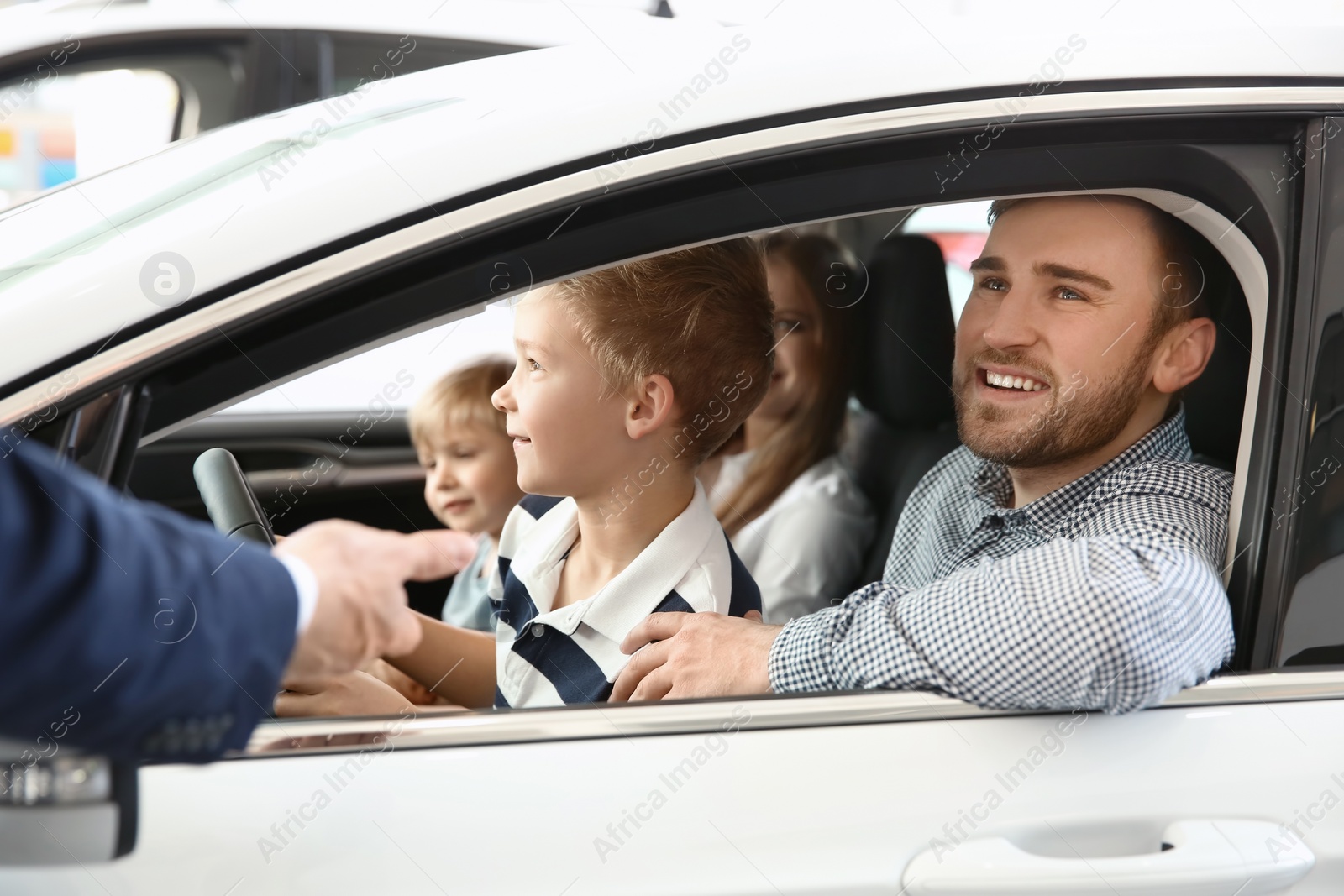 Photo of Young family choosing new car with salesman in salon