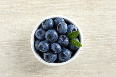 Photo of Bowl of fresh tasty blueberries on white wooden table, top view