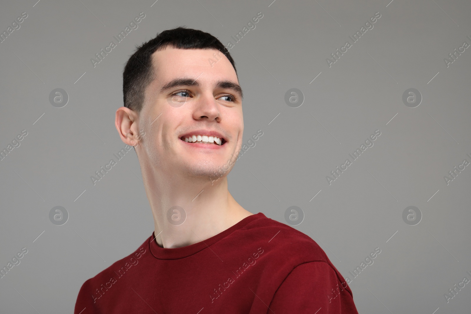 Photo of Handsome young man with clean teeth smiling on grey background, space for text