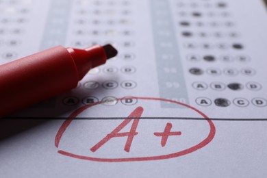 School grade. Letter A with plus symbol on answer sheet and red marker, closeup