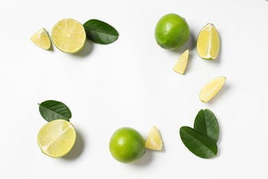 Fresh ripe limes and leaves on white background, flat lay. Space for text