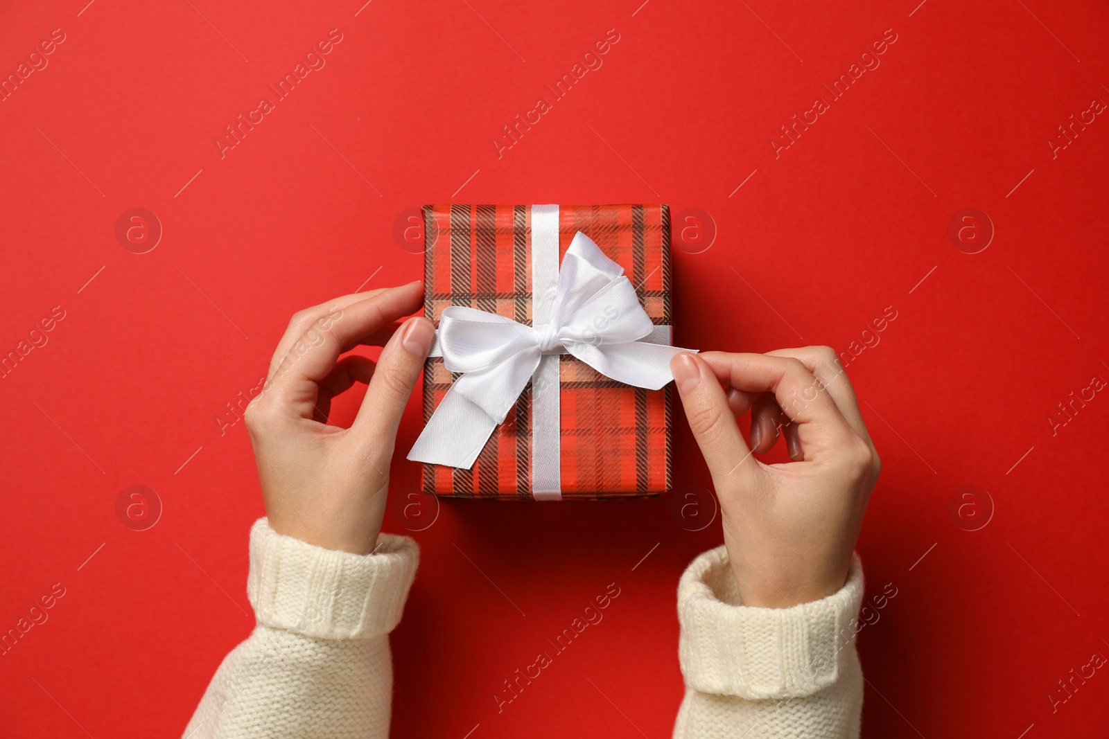 Photo of Woman with Christmas gift on red background, top view