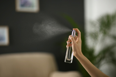Photo of Woman spraying air freshener at home, closeup. Space for text
