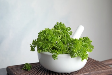 Mortar with fresh green parsley on table