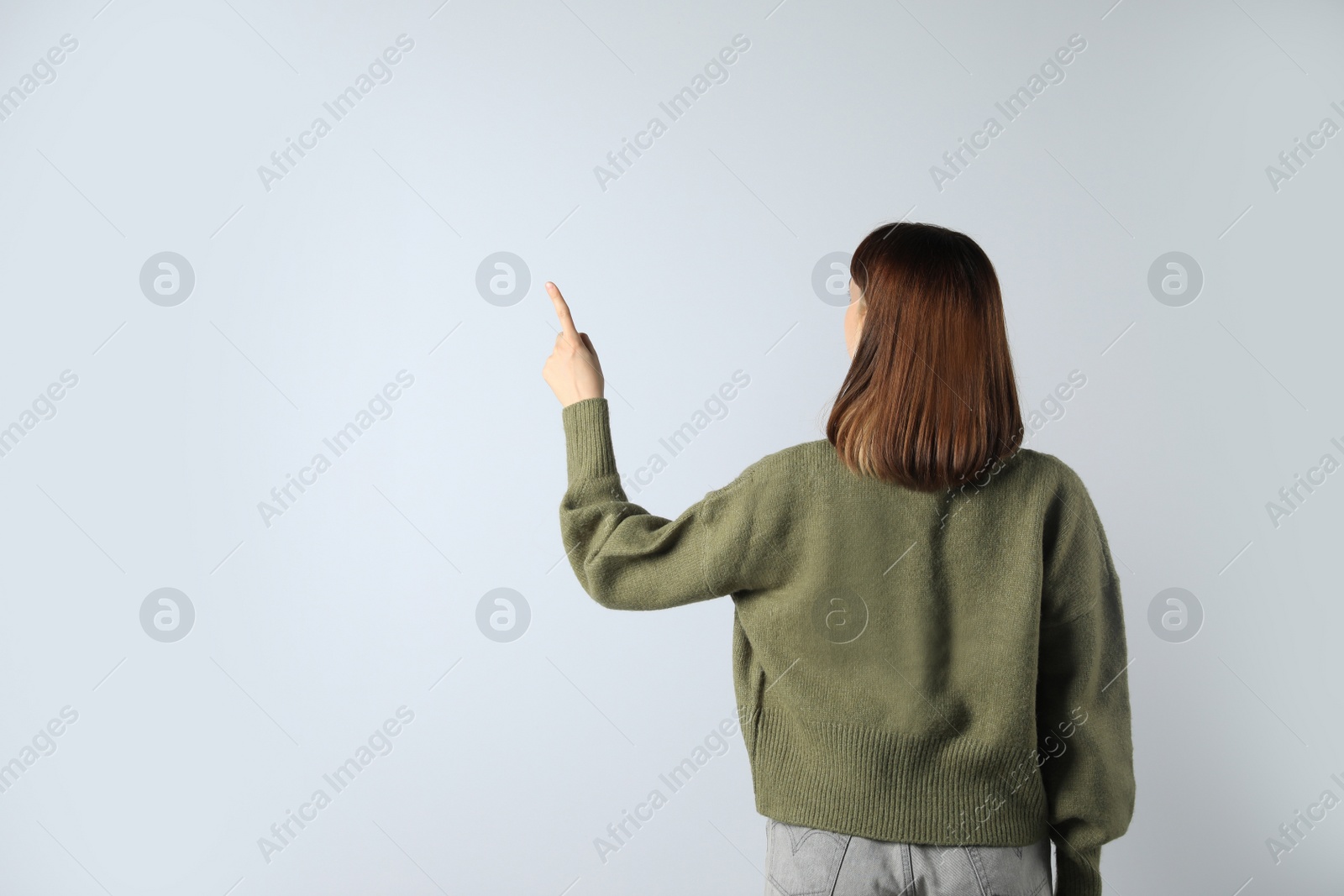 Photo of Young girl pointing on white background, back view. Space for text