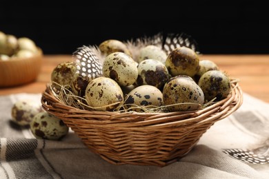 Photo of Speckled quail eggs and feathers on table, closeup