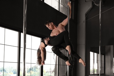 Photo of Young couple dancing in studio with poles