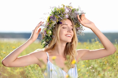 Photo of Young woman wearing wreath made of beautiful flowers in field on sunny day