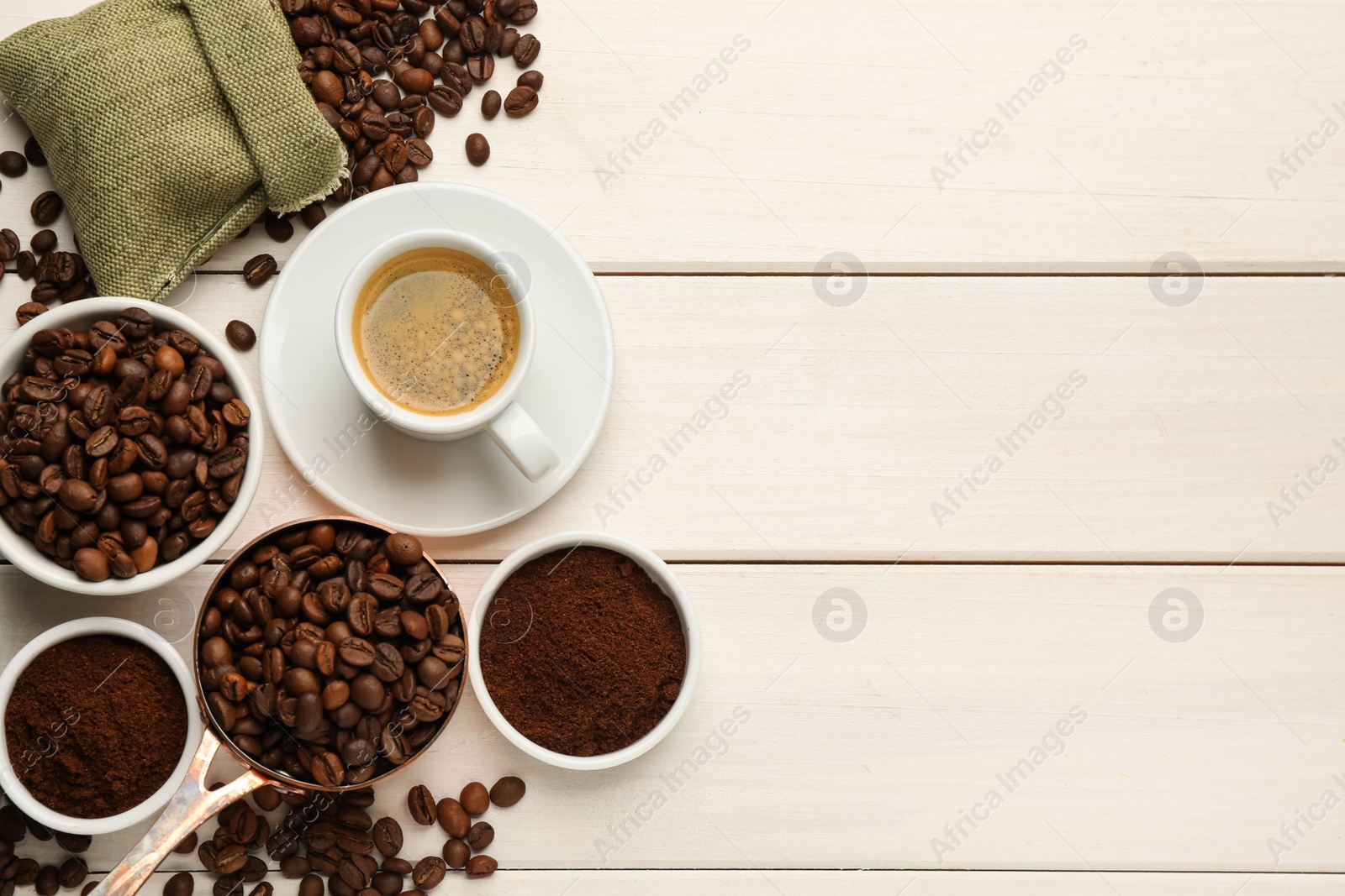 Photo of Coffee beans, powder and cup of drink on white wooden table, flat lay. Space for text