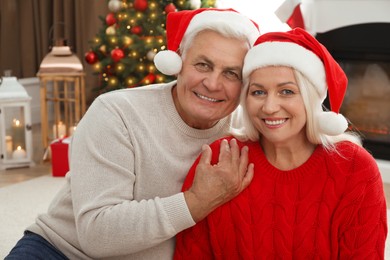 Photo of Happy mature couple in Santa hats at home. Christmas celebration