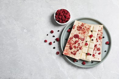 White chocolate bars with freeze dried fruits on grey marble table, flat lay. Space for text