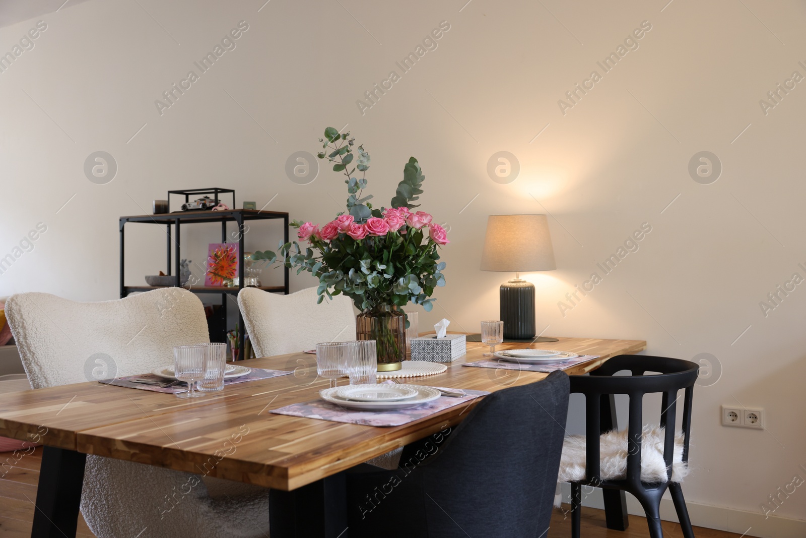 Photo of Beautiful table setting with bouquet in dining room. Roses and eucalyptus branches in vase