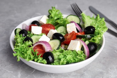 Tasty fresh Greek salad on grey marble table, closeup