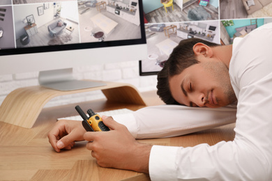 Male security guard sleeping near monitors at workplace