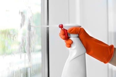 Cleaner washing window glass with detergent indoors, closeup