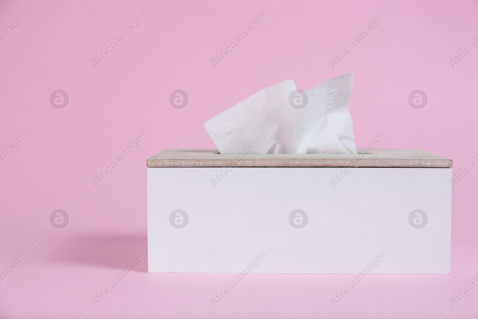 Photo of Holder with paper tissues on pink background