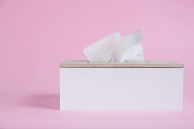 Photo of Holder with paper tissues on pink background