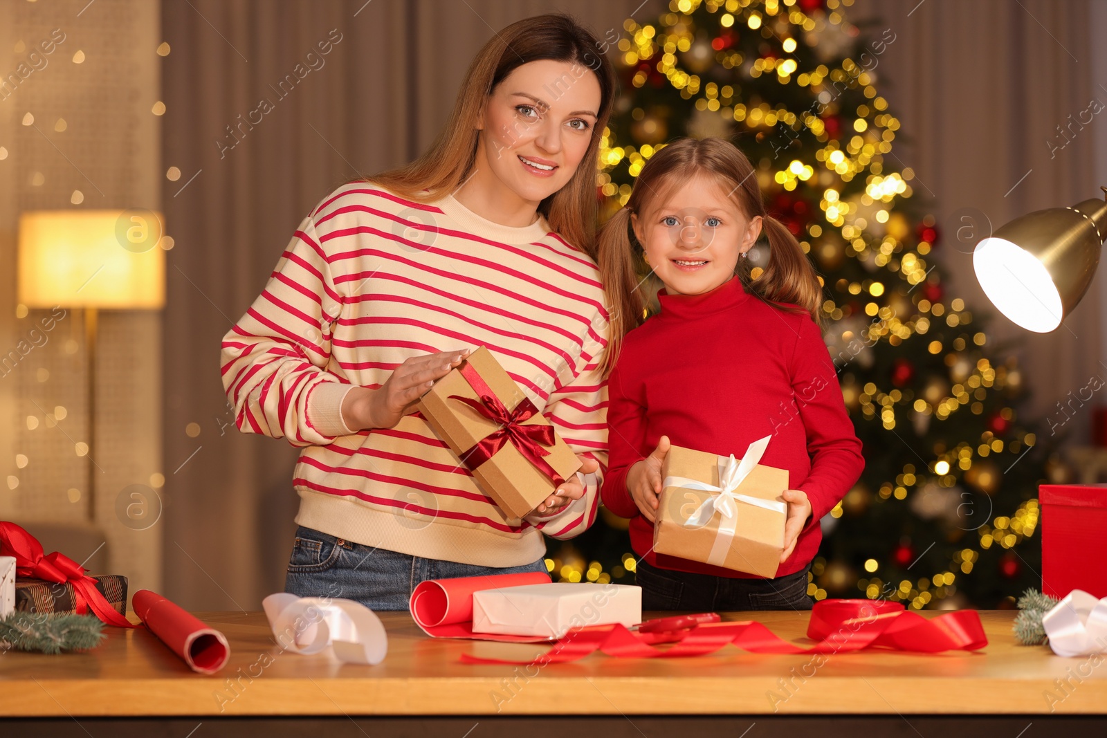 Photo of Christmas presents wrapping. Mother and her little daughter holding gift boxes at home