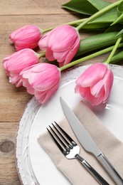 Photo of Stylish table setting with cutlery and tulips on wooden background, above view