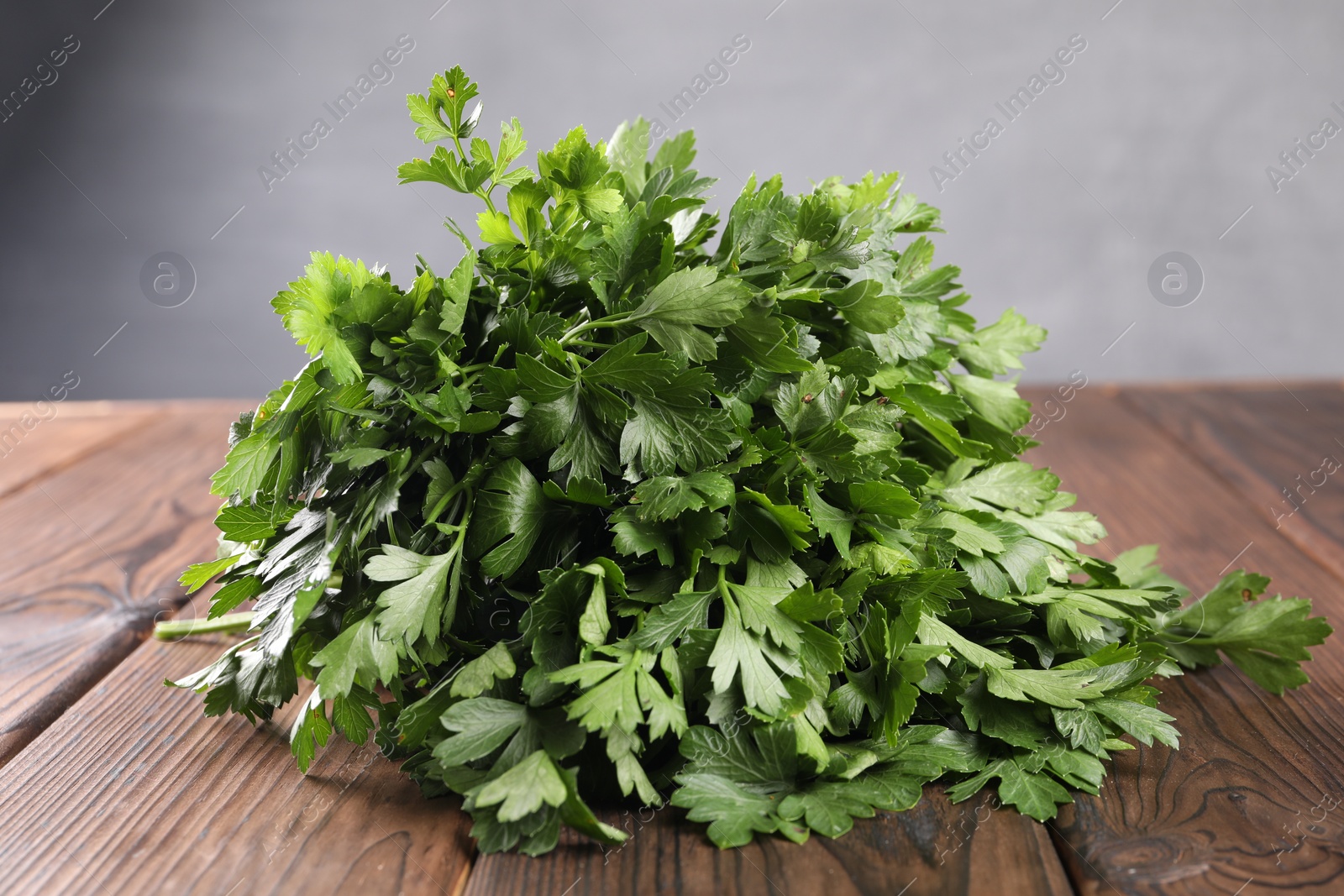 Photo of Bunch of fresh green parsley leaves on wooden table, closeup