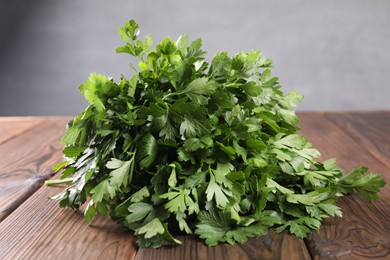 Photo of Bunch of fresh green parsley leaves on wooden table, closeup