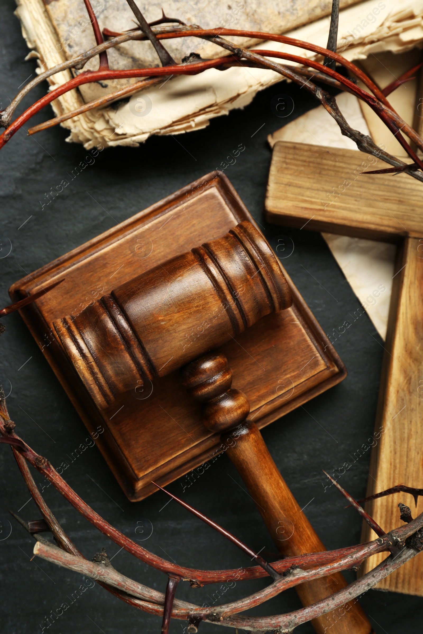 Photo of Judge gavel, wooden cross and crown of thorns on black table, flat lay