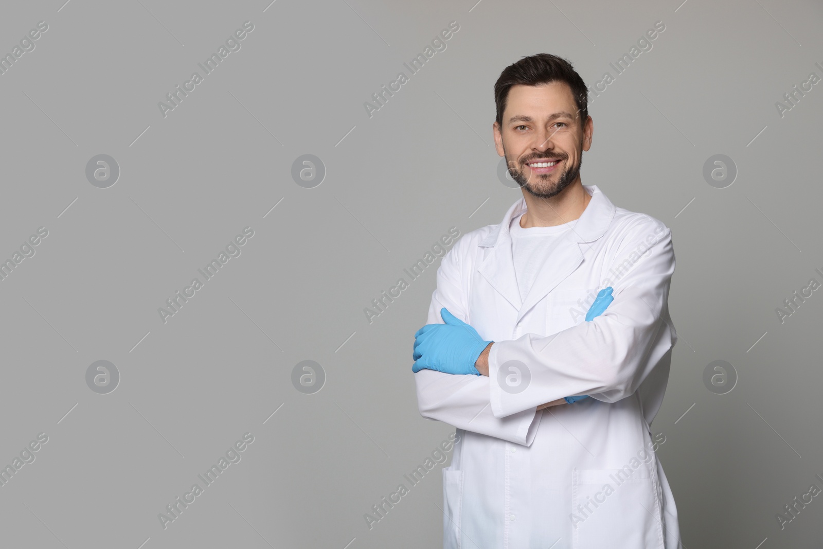 Photo of Doctor or medical assistant (male nurse) in uniform on light grey background. Space for text