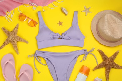 Photo of Flat lay composition with swimsuit and beach accessories on yellow background