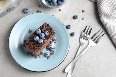 Delicious fresh chocolate cake served with blueberries on grey table, flat lay