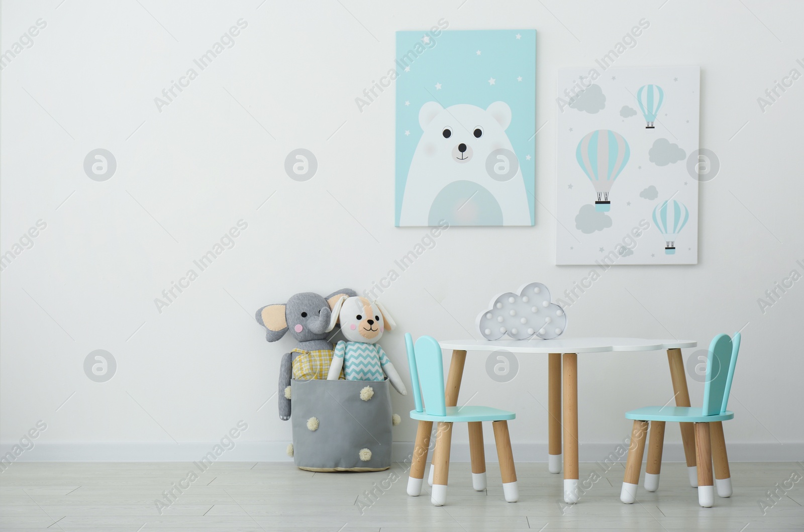 Photo of Adorable wall art, table and chairs with bunny ears in children's room interior