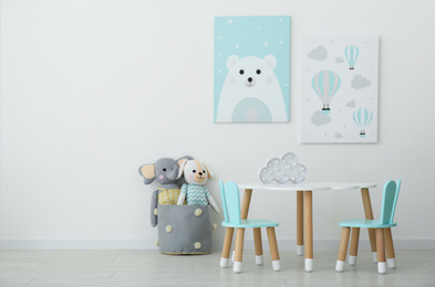 Adorable wall art, table and chairs with bunny ears in children's room interior
