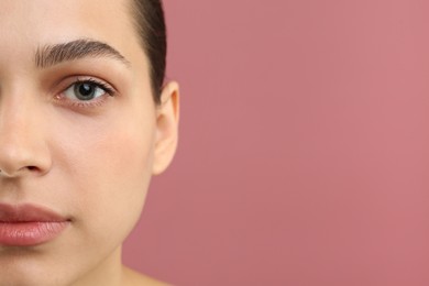 Young woman with perfect eyebrows on pink background, closeup. Space for text